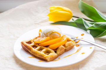 Beautiful festive Belgian waffle breakfast next to a yellow tulip