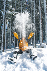Man in yellow jacket throws snow up in the winter forest. Winter holidays and happiness in snow hills. Mountains and forest in frozen days. Season of Christmas time, winter and snow concept with fun.