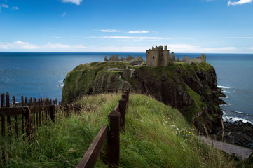 Fototapeta na wymiar dunnottar castel rock beach with sea and stormy clouds and bright boil