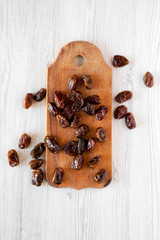 Dried dates on rustic wooden board over white wooden background, overhead view. From above, top view, flat lay. Close-up.