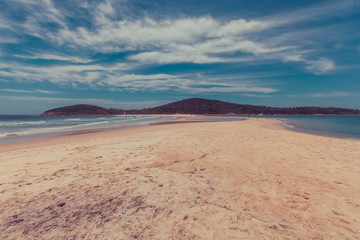 Fototapeta na wymiar People walking on Fingal sand spit near Fingal Island at Fingal Bay, New South Wales, Australia