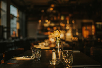 A close up shot of a romantic dinner set up with glassware and a flower. Concept of restaurant business, catering and hospitality. Horizontal image with free copy space for your text.