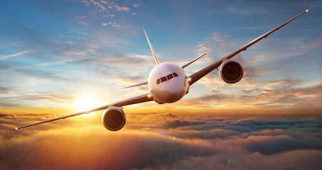 Commercial airplane flying over dramatic sunset
