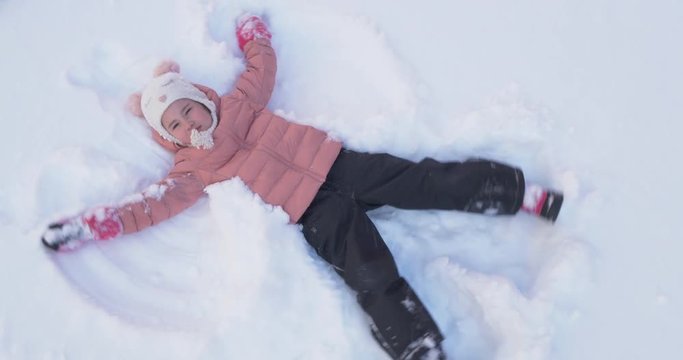 Beautiful little girl making a snow angel