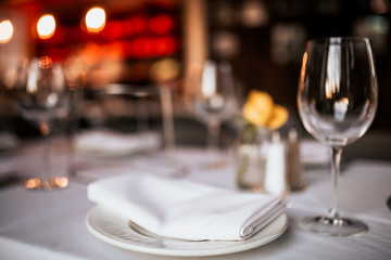 A close up shot of a restaurant table set up with tableware and wine glass. Concept of dining, hospitality and catering. Horizontal image with free space for text.