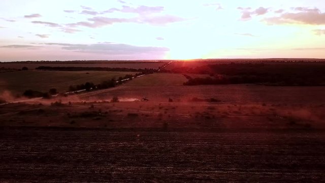 Dust from tractor on red sunset, contre-jeur