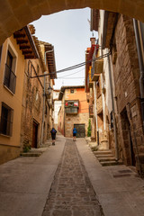 Fototapeta na wymiar Rear view of pilgrims in a steep street in Cirauqui, Spain on the Way of St. James, Camino de Santiago