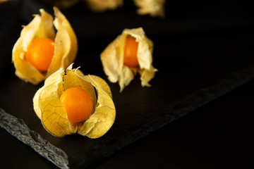 Physalis flowers, fruits isolated on a black background. Orange berry fruits, decorations for cakes.