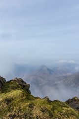 A view from a mountain summit with several other summits and altitude white clouds