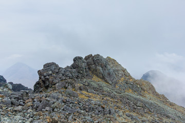 Fototapeta na wymiar A rocky mountain view with a far away summit and altitude white clouds