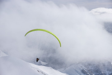 Paragliding at snowy mountains over ski resort at sunny winter day. Caucasus Mountains. Georgia, region Gudauri.