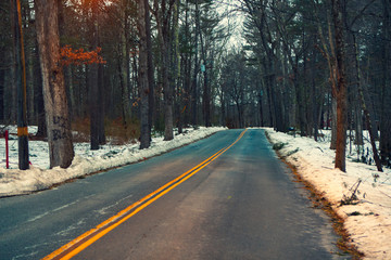 Acton, United States, February 27, 2019. Forest road with double yellow line in winter time, Massachusetts, United States