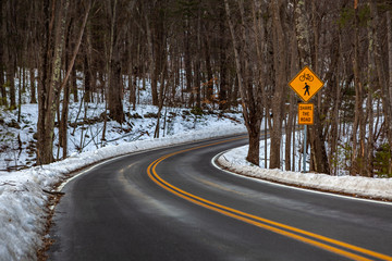 Acton, United States, February 27, 2019. Forest road with double yellow line in winter time,...