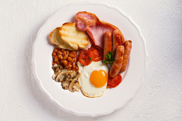 Full English or Irish breakfast with sausages, bacon, eggs, tomatoes, mushrooms and beans. Nutritious and healthy morning meal. View from above, top studio shot © freeskyline