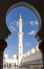 View of a tower of the white mosque of Abu Dhabi framed through an arch