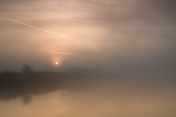 fiume  con argine all'alba con nebbia del primo mattino