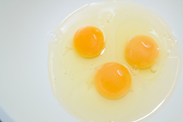 Three broken chicken eggs in a white mixing bowl