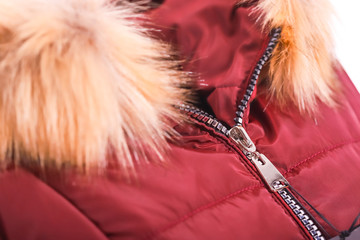 Close up of zipper on red jacket with fur , winter fashion outfit. Jacket isolated on white background.