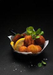 Fried Spanish bacalao croquettes in iron pan made with breaded salted codfish and served as...