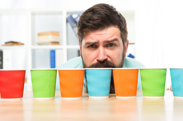 Choose from alternatives. Man bearded choosing one of lot colorful paper cups. Alternative concept....