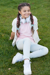Stylish happy child relax on green grass. little girl listen music. Spring mood. Mp3 player. happy...