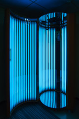 vertical Solarium with glowing blue light ultraviolet lamps
