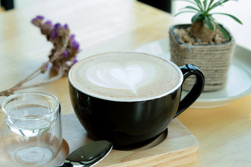 Latte art coffee in the morning time with sunlight on wooden table background at coffee shop.