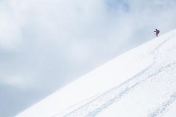 Obraz premium Skier in red pointing down powder covered slope in Japan