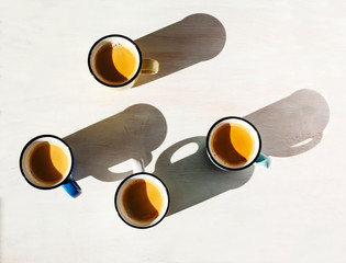  Cups of coffee. Four cups of Espresso on a table back lit by the sun casting a long shadows