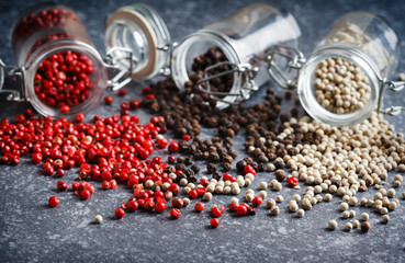 Pink, white and black peppers in a glass jars