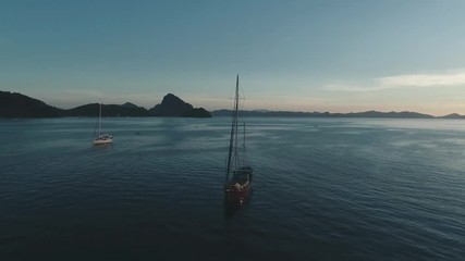 Aerial drone view of boats anchored in the bay with clear and turquoise water on the sunset. Boat and yacht in the tropical lagoon. Tropical landscape. El Nido, Palawan island, Philippines.