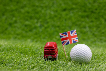 Double decker bus with golf ball on green with Union Jack flag