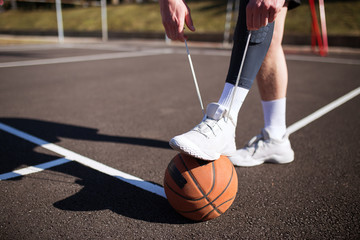 Naklejka premium Basketball player tying shoelace