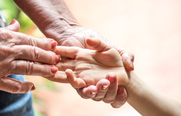 hand of an elderly woman holding a child's hand