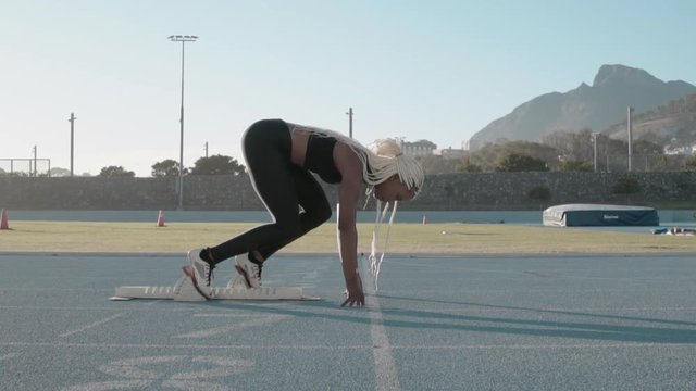 Side view of a female athlete starting her sprint on a running track. Runner taking off from the starting blocks on running track.