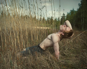 portrait of a young man with no shirt on involved in sports in the field among the tall grass