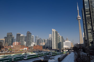 Fototapeta na wymiar Commuter GO trains and VIA train on tracks to Union Station Toronto with CN Tower and cityscape skyline of highrise buildings