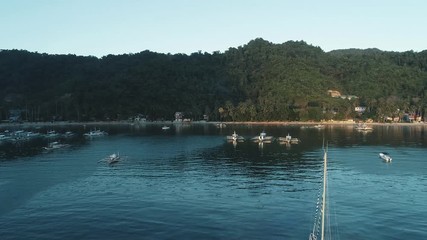 Aerial drone view of boats anchored in the bay with clear and turquoise water on the sunset. Boat and yacht in the tropical lagoon. Tropical landscape. El Nido, Palawan island, Philippines.