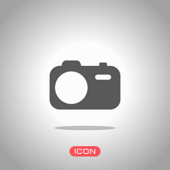 Simple photo camera. Technology icon. Icon under spotlight. Gray background