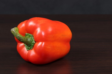 One large sweet bell pepper on the table with a dark background. Red pepper.