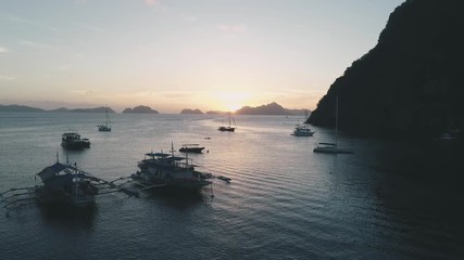 Aerial drone view of boats anchored in the bay with clear and turquoise water on the sunset. Boat and yacht in the tropical lagoon. Tropical landscape. El Nido, Palawan island, Philippines.