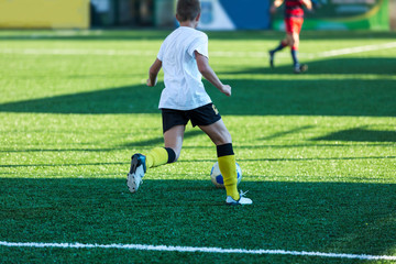 Fototapeta premium Football training soccer for kids. Boy runs kicks dribbles soccer balls. Young footballers dribble and kick football ball in game. Training, active lifestyle, sport, children activity concept 