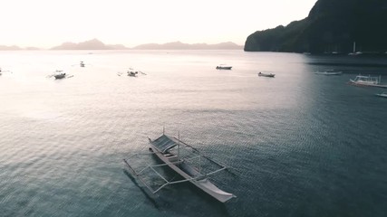 Aerial drone view of boats anchored in the bay with clear and turquoise water on the sunset. Boat and yacht in the tropical lagoon. Tropical landscape. El Nido, Palawan island, Philippines.