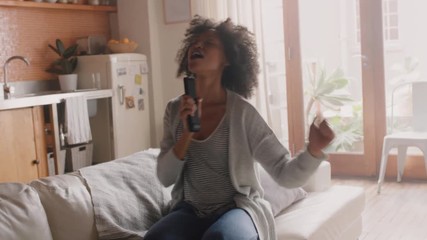 happy woman singing at home having fun celebrating successful lifestyle dancing enjoying karaoke music entertainment on weekend