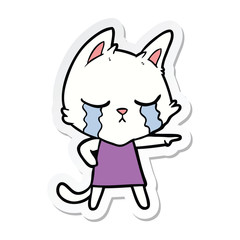 sticker of a crying cartoon cat in dress pointing