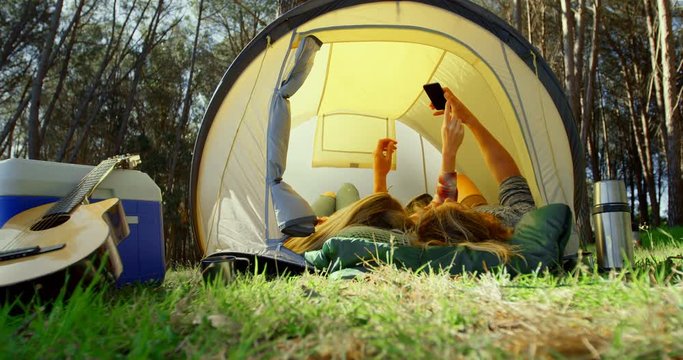 Young couple clicking selfie with mobile phone in tent 4k