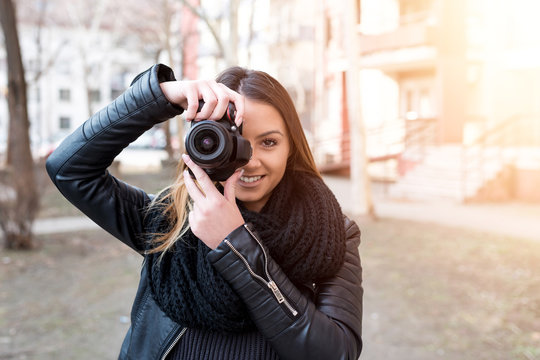 Young woman taking pictures outside.