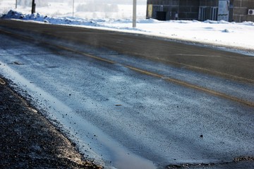 The spring sun heats asphalt after winter and evaporates. Wet road in early spring.