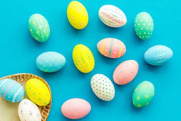 Easter traditions. Colorful Easter eggs in basket on blue background top view