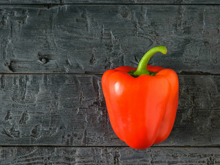 Beautiful ripe red bell pepper on a black wooden table. Vegetarian food. The view from the top. Flat lay. © kvladimirv